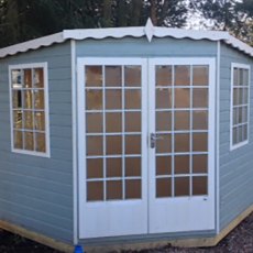 7 x 7 Shire Gold Windsor Corner Summerhouse - front view painted blue with white fascia windows and